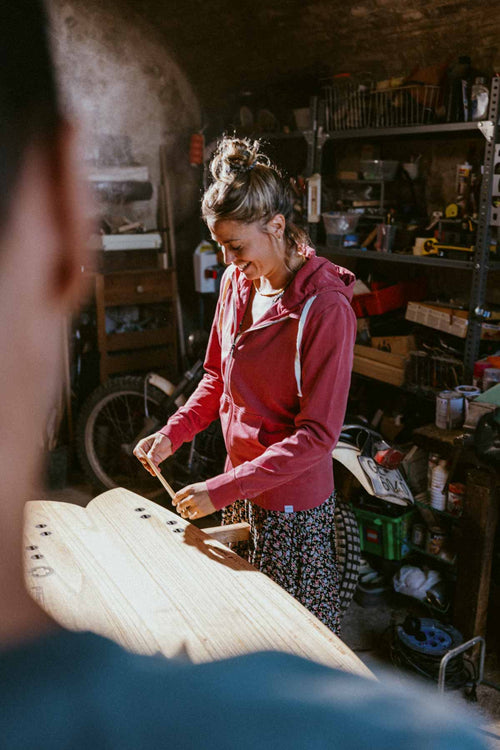 Chica con tabla surf y con Sudadera Bonito algodón orgánico peruano capucha cremallera roja hecha en Barcelona 